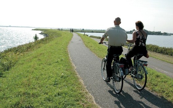 A couple cycling near a river