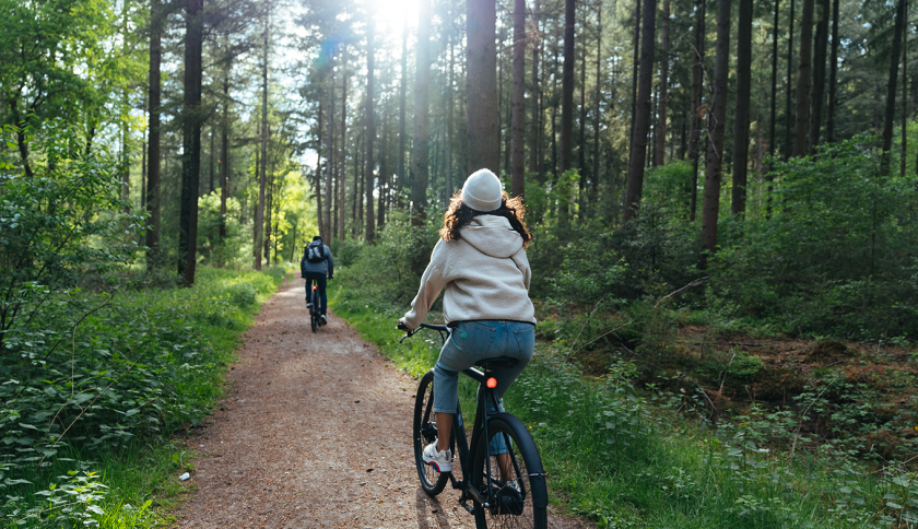 Two people cycling on electric bikes in the forest
