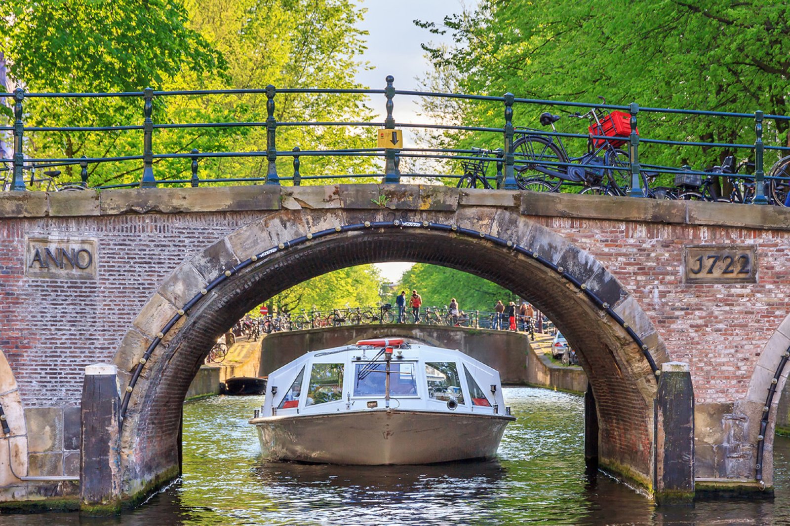 Canal cruise boat under an old arch bridge