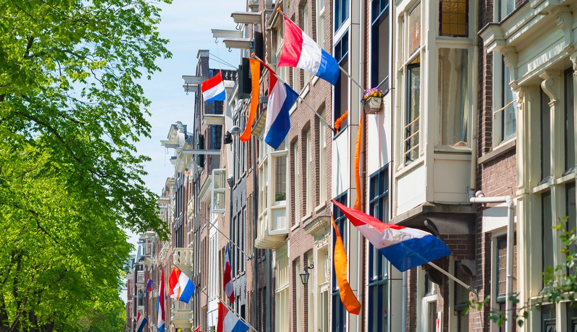 Canal houses with Dutch flags and orange pennant during King's Day