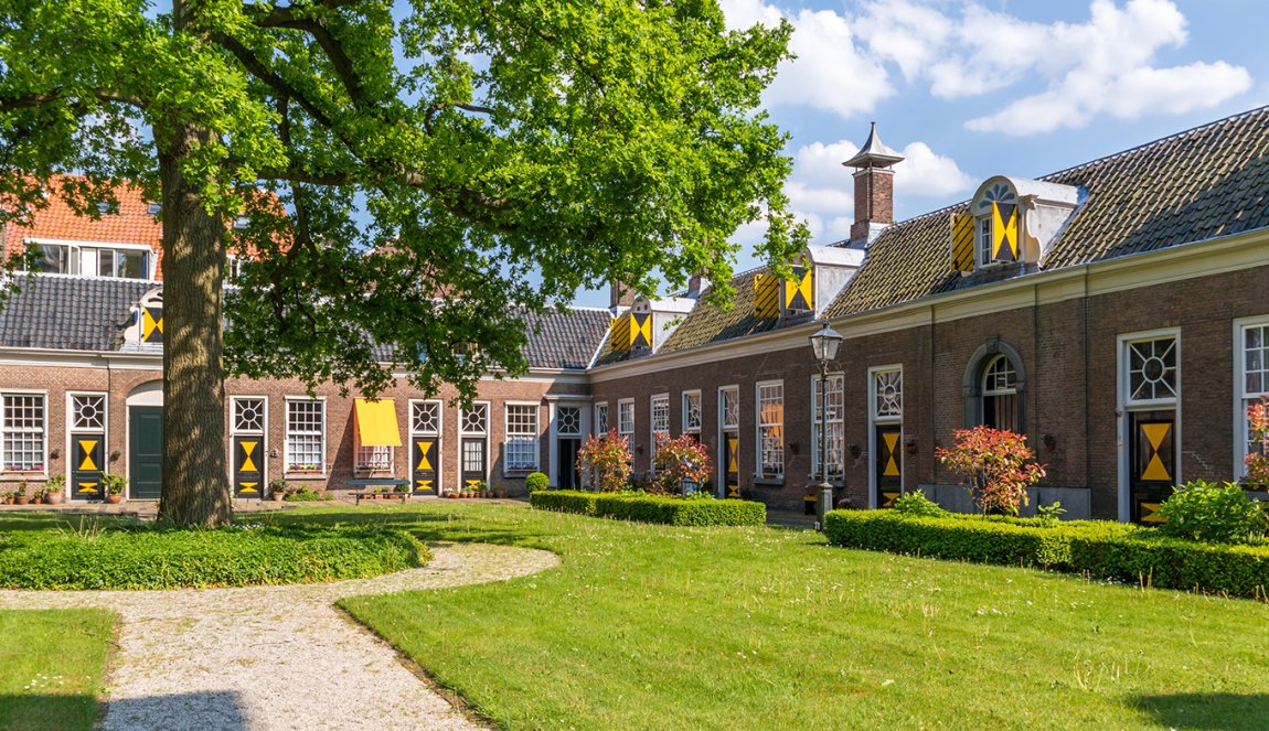 Green courtyard surrounded by old almshouses in Hofje van Staats in city of Haarlem