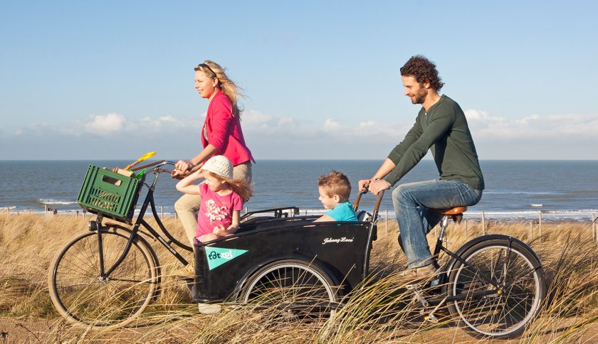 Young family cycling in the dunes with sea in background Scheveningen