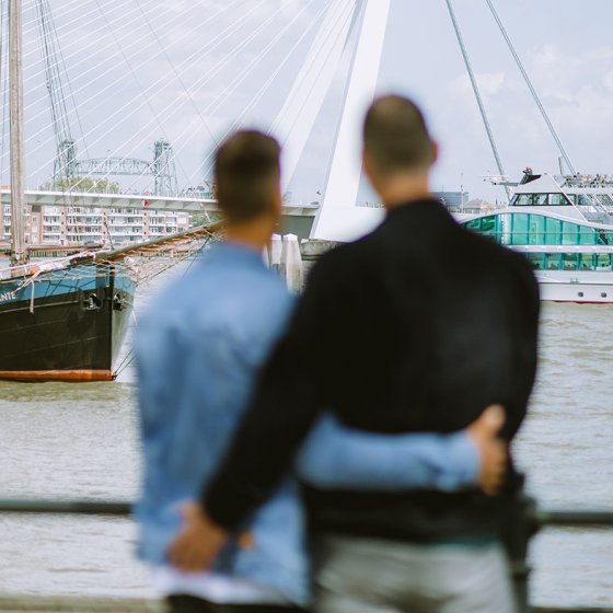 Couple looks arm in arm at the Erasmus Bridge