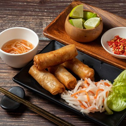 Fried spring rolls with lime and noodles served in bowl isolated on table top view