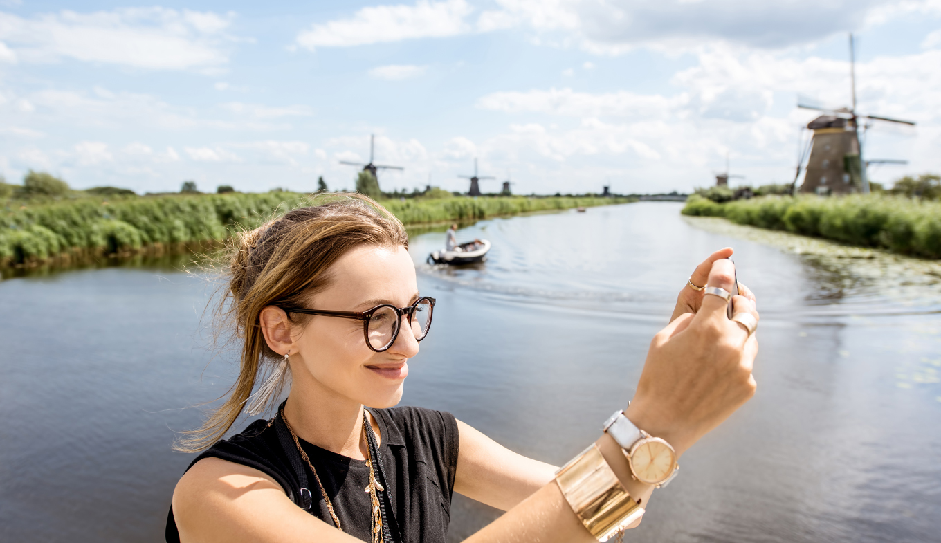 Young woman tourist with photo camera background windmills Young woman tourist with photo camera background windmills