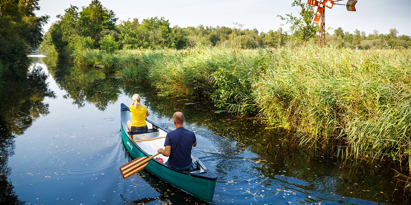 Canoeing past windmills and reed beds in National Park Weerribben-Wieden