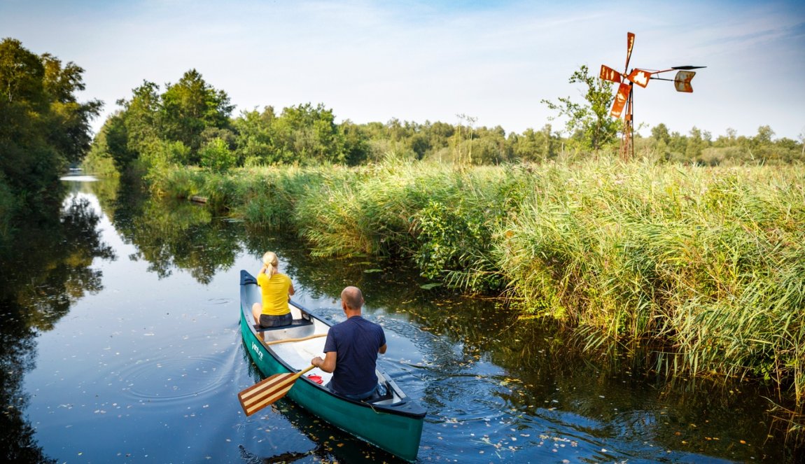 Canoeing past windmills and reed beds in National Park Weerribben-Wieden.