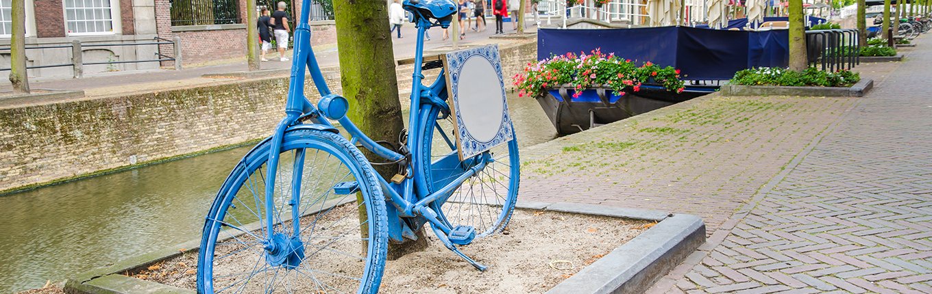 Old Dutch blue bicycle parked by a canal in Delft Old Dutch blue bicycle parked by a canal in Delft