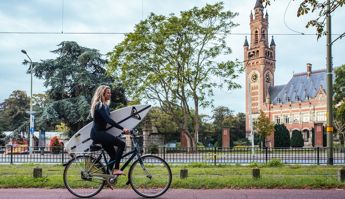 Women with a surfboard riding on a bike