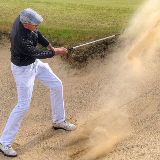 Golf player plays ball from the bunker
