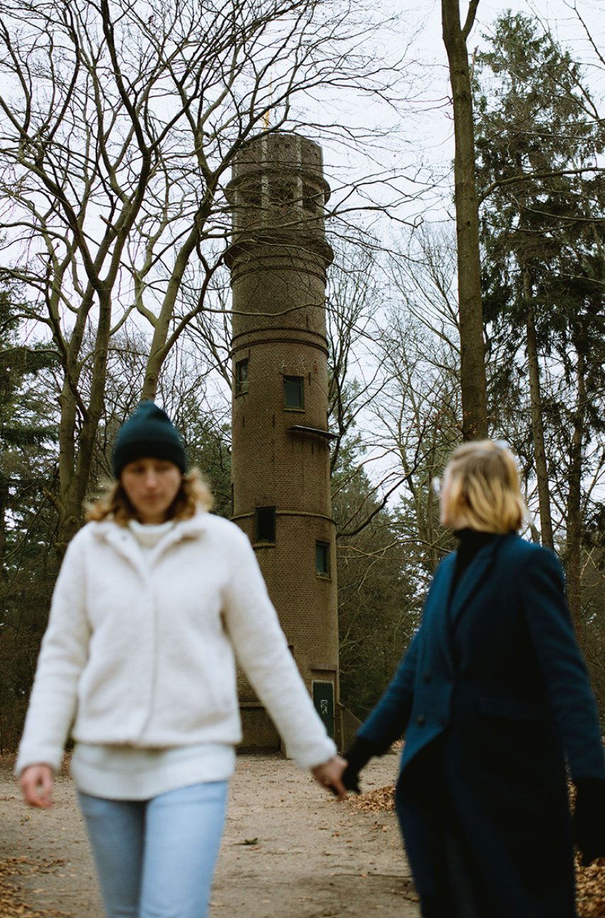 Couple walking hand in hand with the Belvedere Tower Lochemse Berg in the background, Barchem