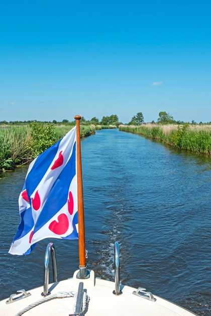 Boat with flag of Friesland sailing through the Alde Feanen National Park