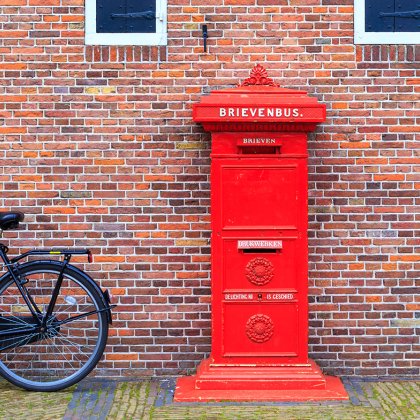 Big red vintage mailbox (brievenbus) against a brick wall