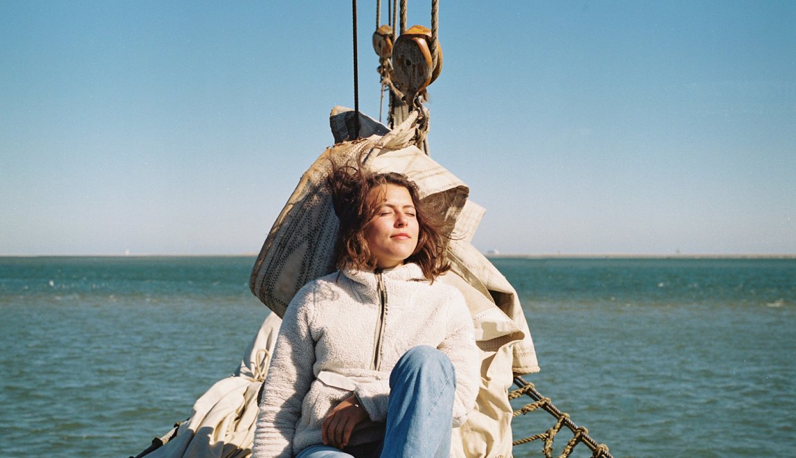 Young woman relaxed in the sun on a sailboat in the Wadden Sea