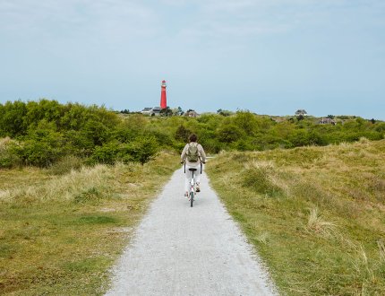 Cyclist on Schiermonnikoog with the lighthouse in view Cyclist on Schiermonnikoog with the lighthouse in view