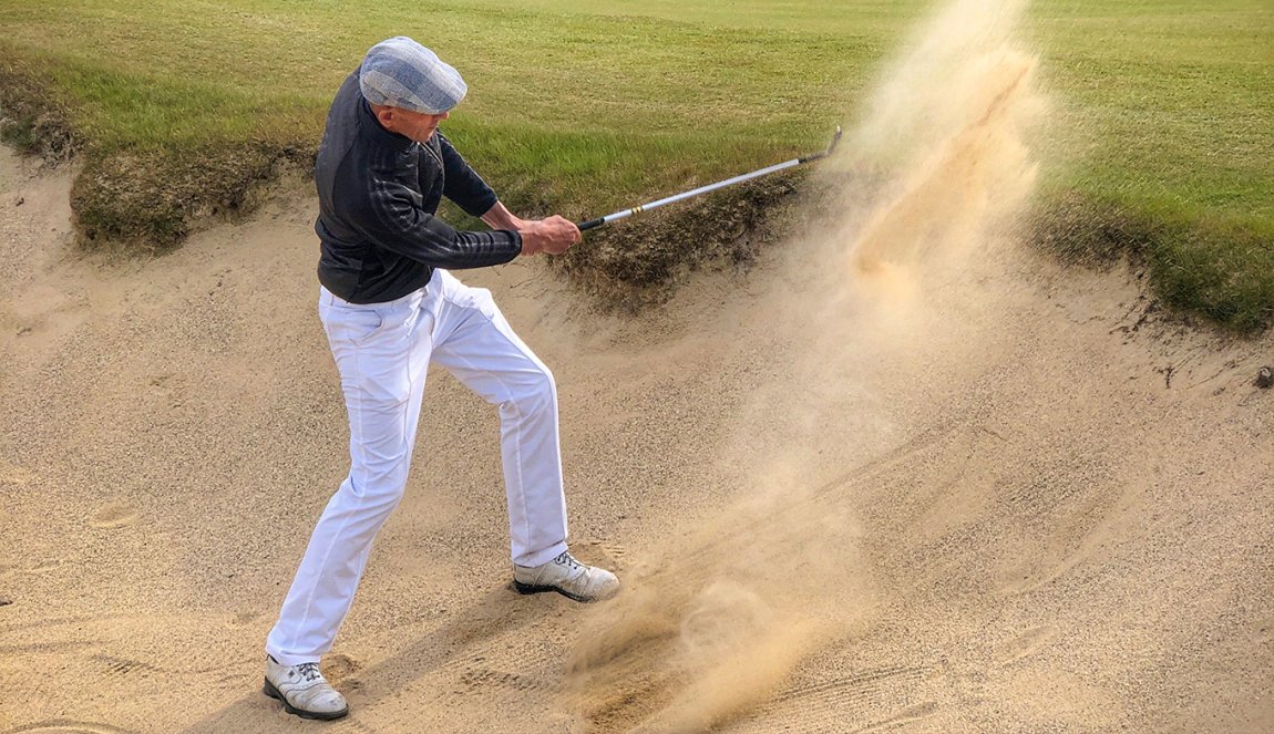 Golf player plays ball from the bunker