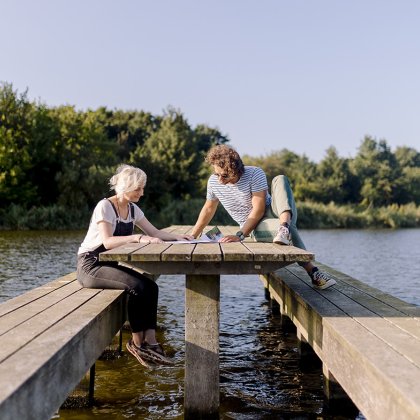 Man and woman sitting on wooden bench in the water Lauwersmeer
