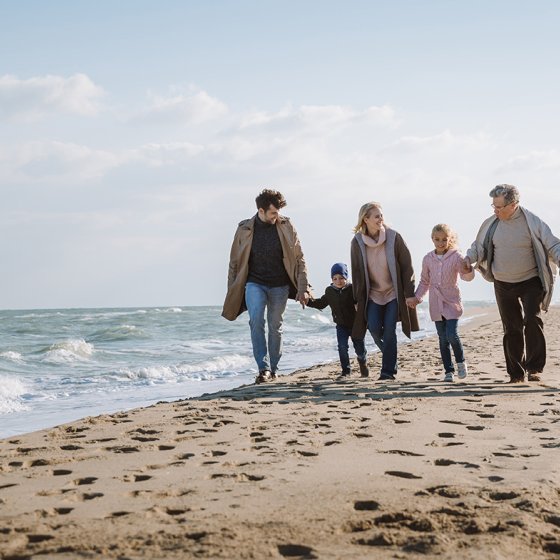 Family walk together on beach by the sea