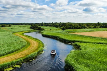 Boat sailing in water through Dutch landscape