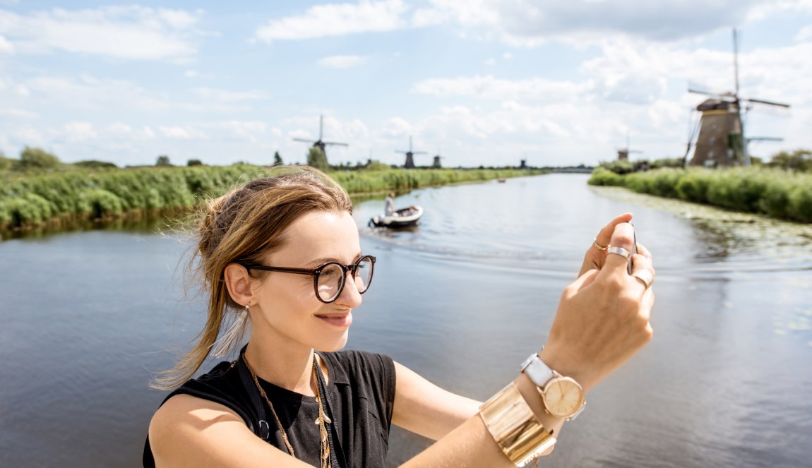 Young woman tourist with photo camera background windmills