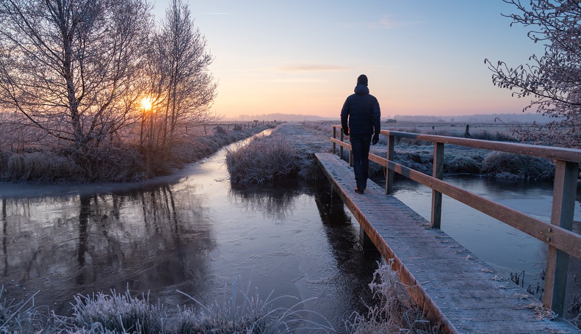 Man walks across footbridge in winter
