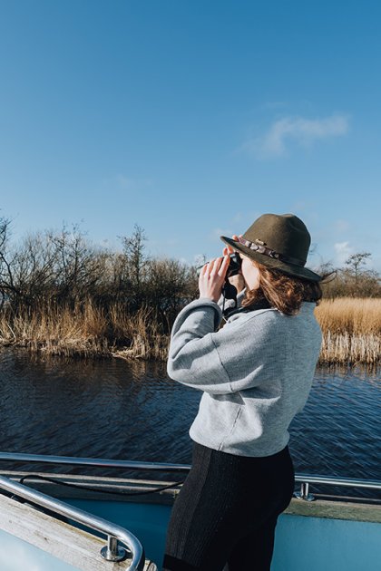Girl on a boat sailing through the Alde Feanen while looking through a binocular