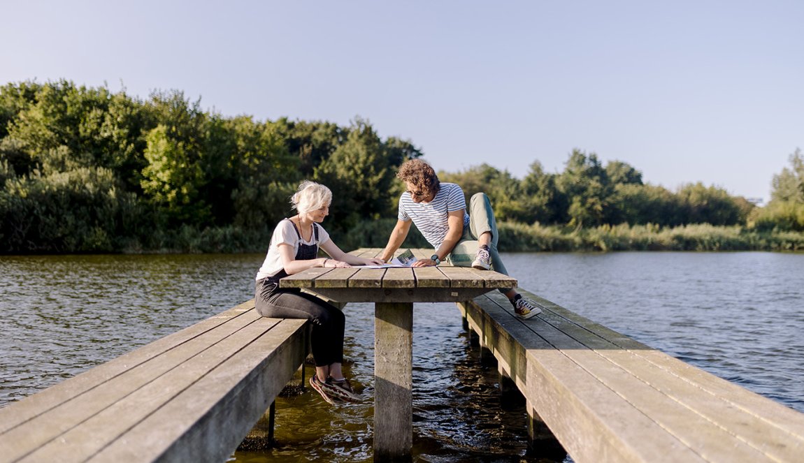 Man and woman sitting on wooden bench in the water Lauwersmeer
