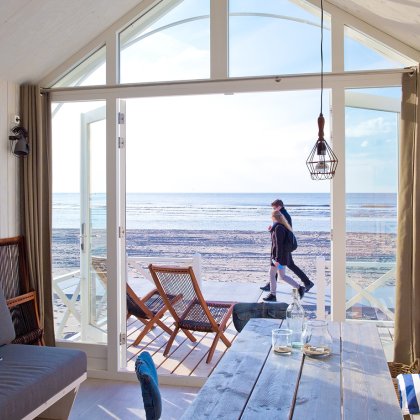 View from a beachfront holiday home near The Hague as a couple walks along the North Sea beach, perfect for a relaxing seaside getaway