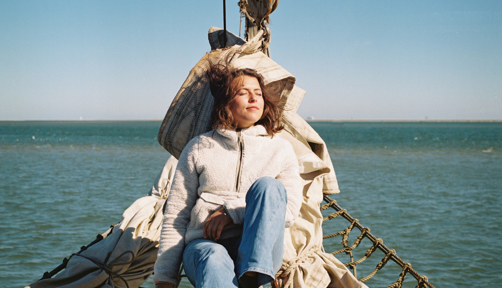 Young woman relaxing in the sun on a sailing boat in the Wadden Sea Young woman relaxing in the sun on a sailing boat in the Wadden Sea