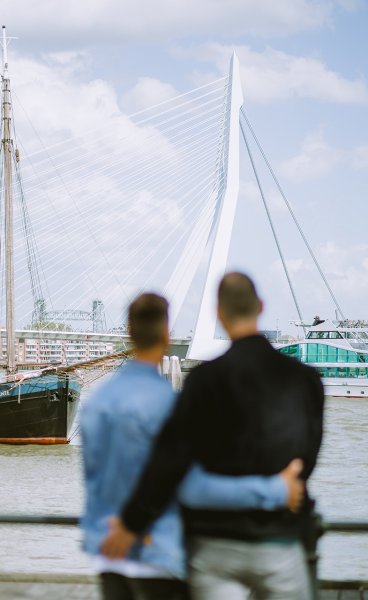 Couple looks arm in arm at the Erasmus Bridge