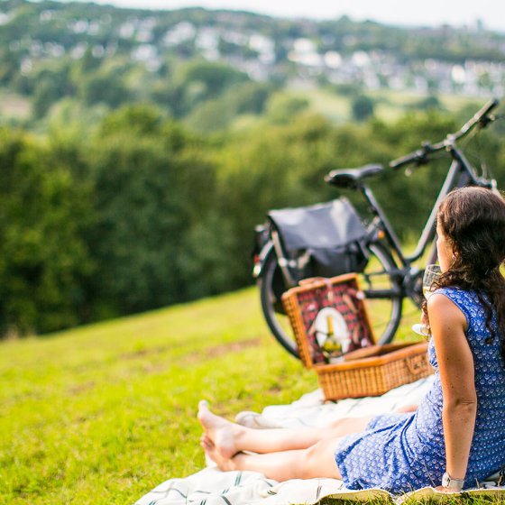 A couple on a bicycle, enjoying a picnic whilst gazing out over the rolling hills of the South Limburg countryside