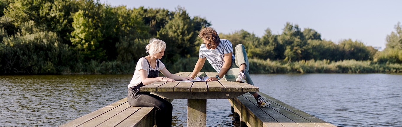 Man and woman sitting on wooden bench in the water Lauwersmeer Man and woman sitting on wooden bench in the water Lauwersmeer