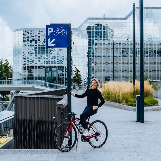 Belle de Gast sitting on bike holding on to pole