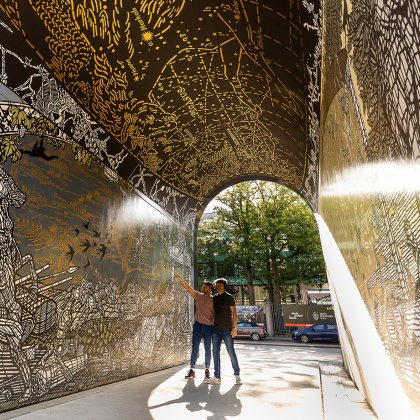 Two visitors admire the artistic murals and detailed illustrations inside the Blind Walls Gallery at Achter de Lange Stallen in Breda