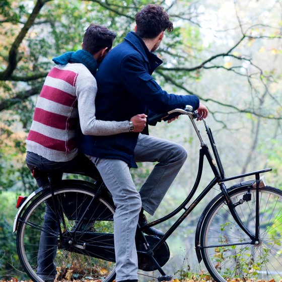 Two men enjoy a bike ride together in a green park in the Netherlands