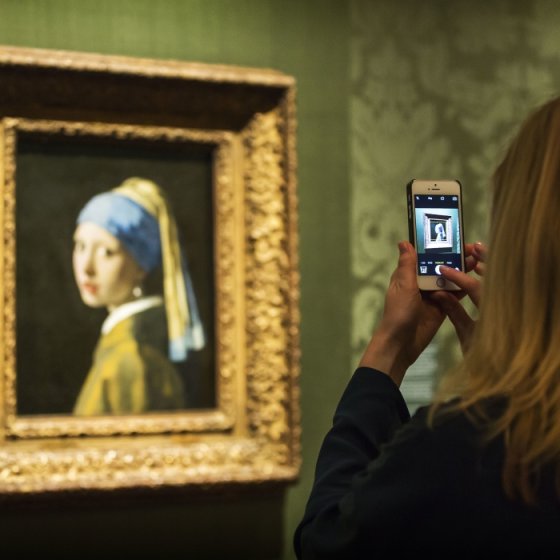 Visitor photographing Vermeer&rsquo;s Girl with a Pearl Earring at the Mauritshuis in The Hague, home to some of the Netherlands&rsquo; most iconic Dutch Master paintings