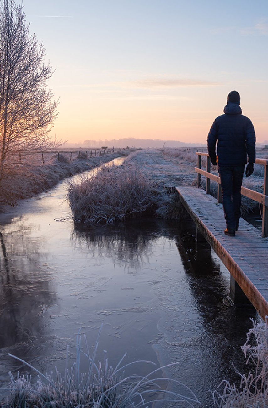 Man walks across footbridge in winter 