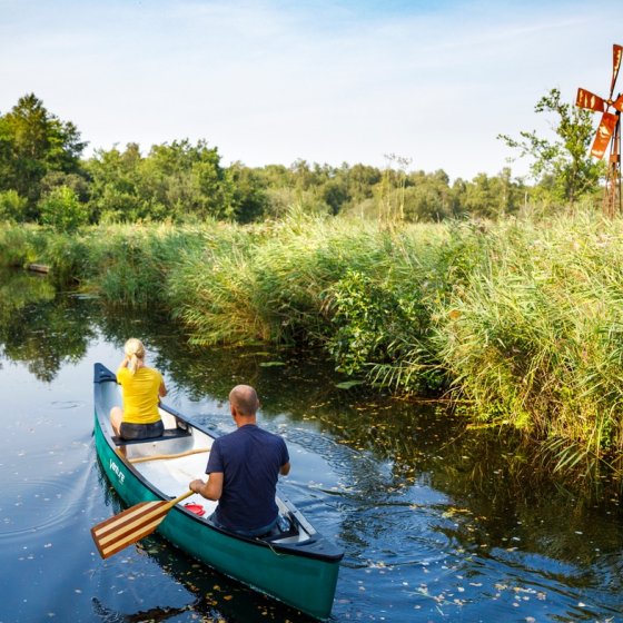 Canoeing past windmills and reed beds in National Park Weerribben-Wieden.