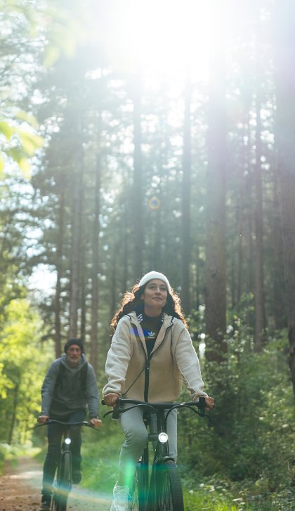 Cyclists in the forest with sun through the trees