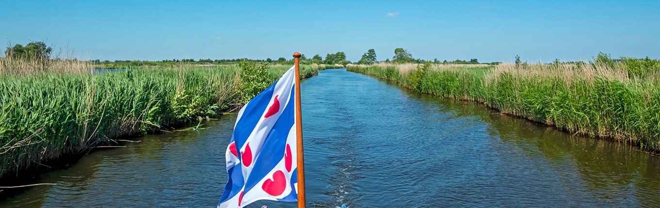 Boat with flag of Friesland sailing through the Alde Feanen National Park Boat with flag of Friesland sailing through the Alde Feanen National Park
