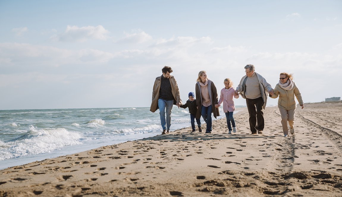 Family walking on the beach with grandparents