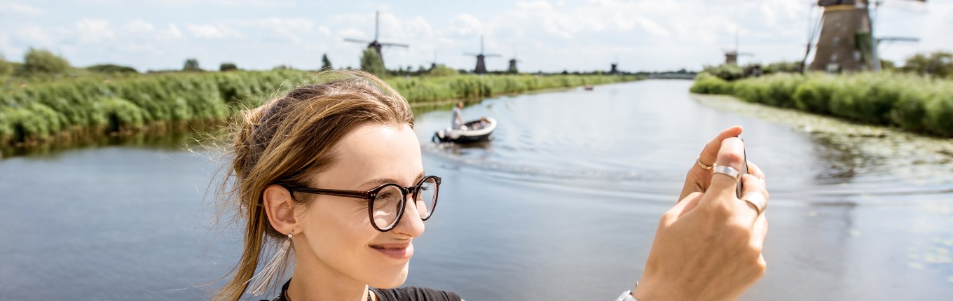 Young woman tourist with photo camera background windmills