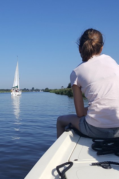 girl sitting on the edge of the boat looking at the Alde Feanen and the boats
