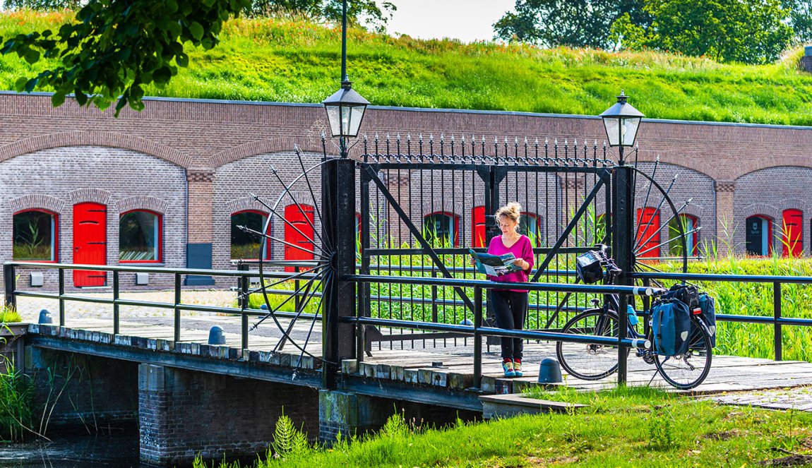 Cyclist looking at a map of the New Dutch Waterline - Fort Voordorp