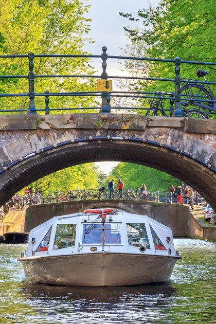 Canal cruise boat under an old arch bridge