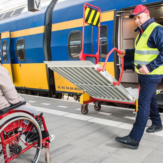 Station assistance; lady in wheelchair gets help to enter train.