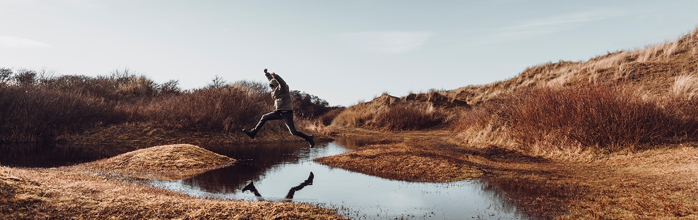 Man jumps over a puddle on Wadden Island Texel Man jumps over a puddle on Wadden Island Texel