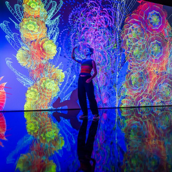 Visitor surrounded by a colourful immersive floral installation at Flowers Forever in Kunsthal Rotterdam