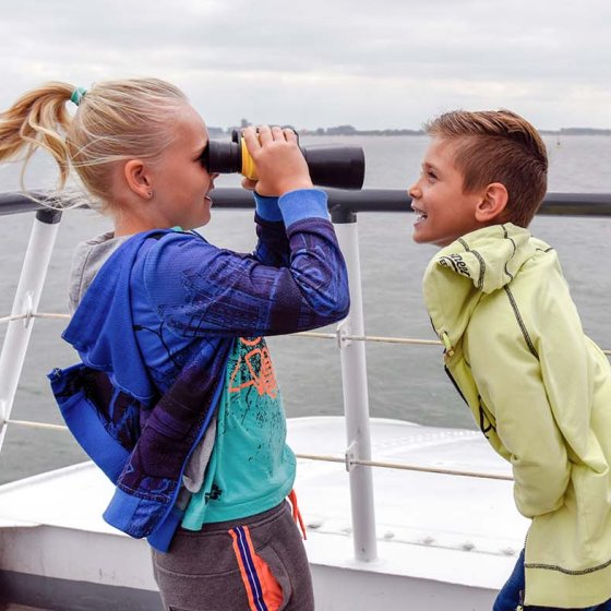 Children with binoculars in the wind on the deck of the Westerschelde Ferry