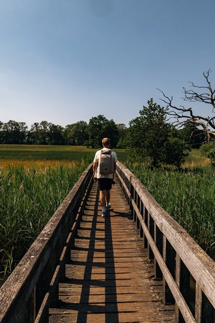 Walking across wooden walkway with backpack Drentsche Aa 